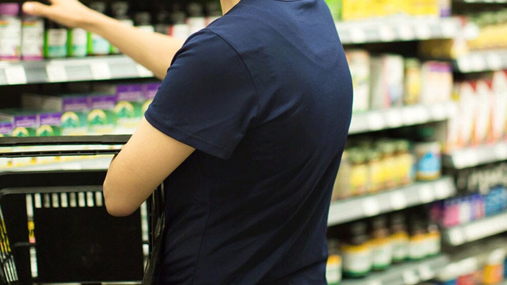 grocery shopper picking up supplement from shelves