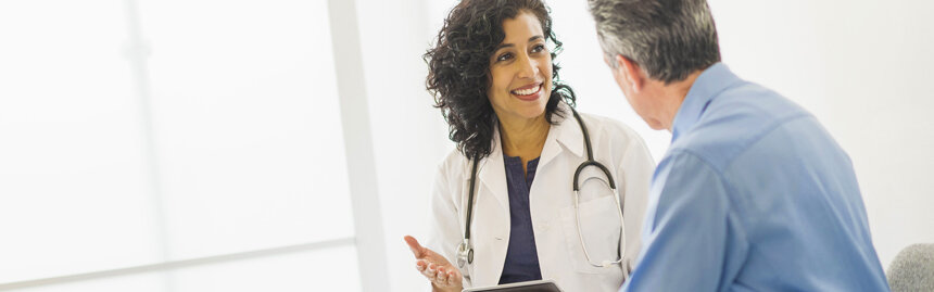 Healthcare provider listening to a male patient during a one-on-one consultation.