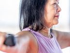 Older adults participate in a strength-training class, lifting dumbbells with arms extended during a group fitness session.