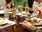 Family eating at dining table with full plate, champagne, and wine