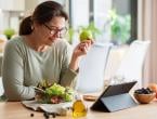 woman eating salad with fruit while reading