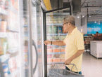 shopper opening fridge door in grocery store