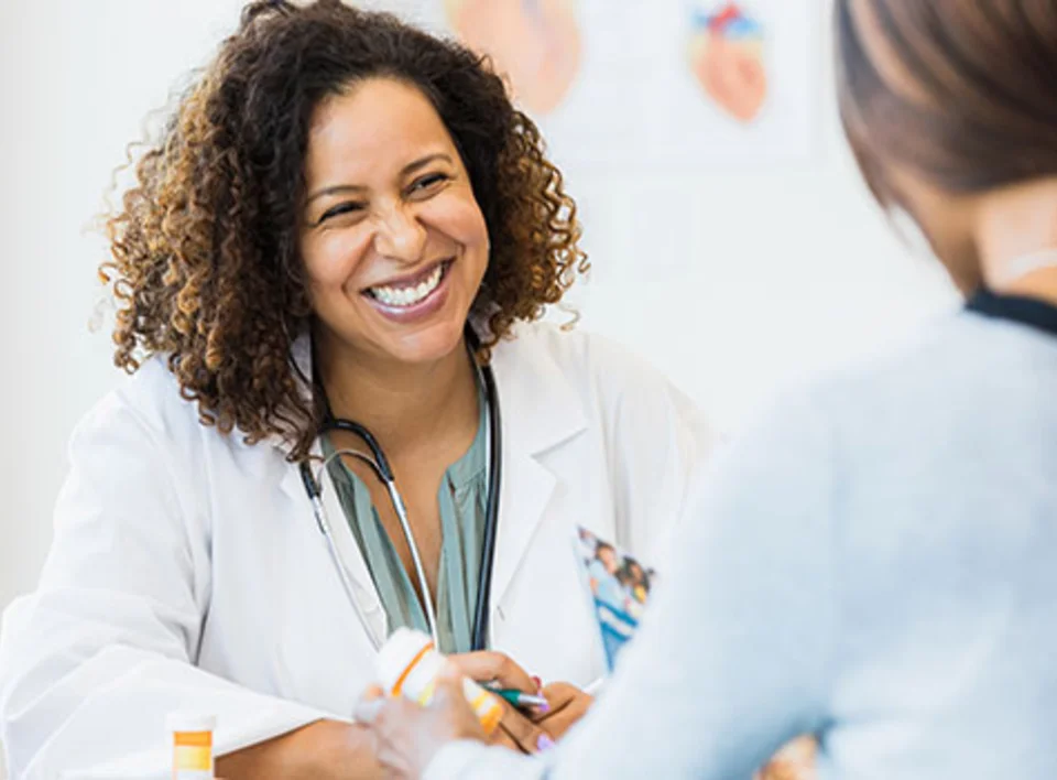 A physician smiles at her patient.