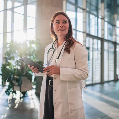 Female-doctor-smiling-and-holding-digital-tablet