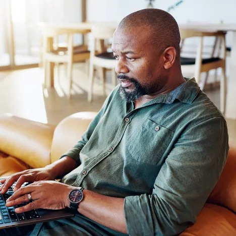 african-man-home-laptop-sofa-online-insurance-news