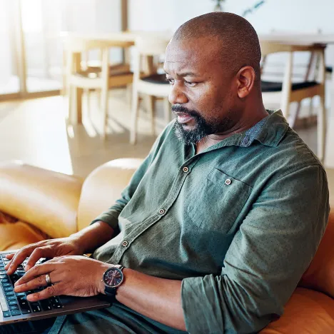 african-man-home-laptop-sofa-online-insurance-news