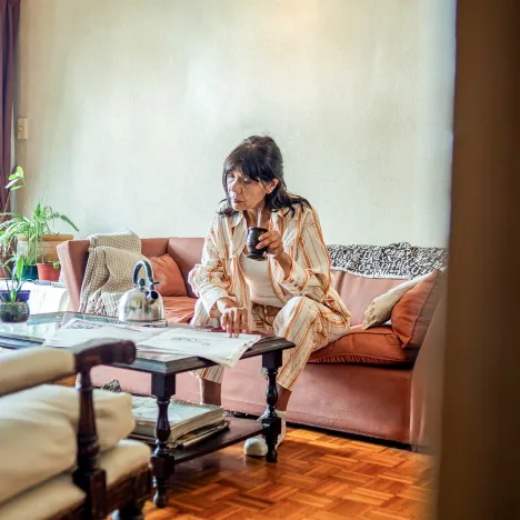 elderly-woman-reading-newspaper-at-home-living-room