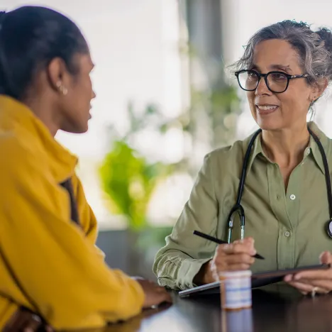 female-doctor-consulting-patient-talking-at-desk-medical-appointment