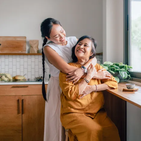 smiling-woman-hugging-mother-kitchen-drinking-tea-family-moments
