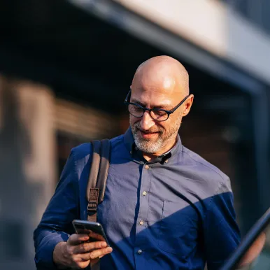 businessman-walking-in-city-with-mobile-phone-and-backpack